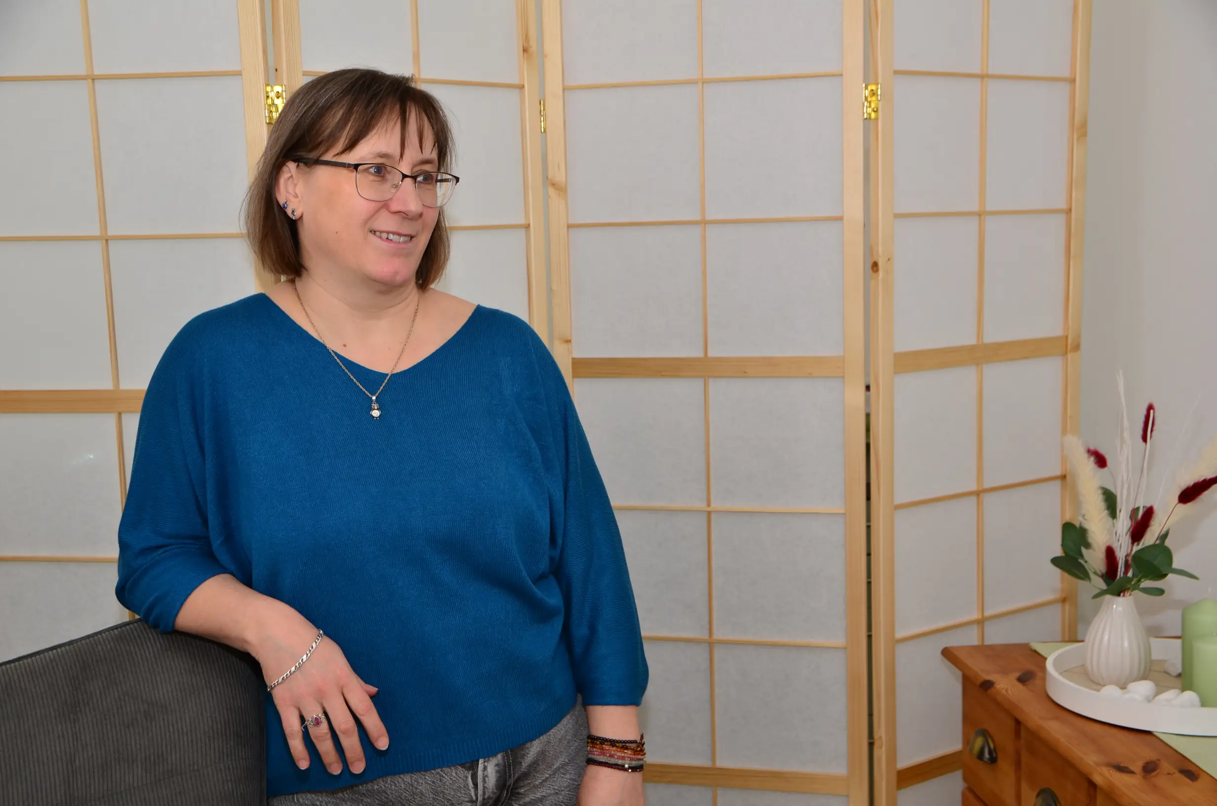 Brigitte Nietzel stützt sich an einer Stuhllehne ab und blickt in den Raum